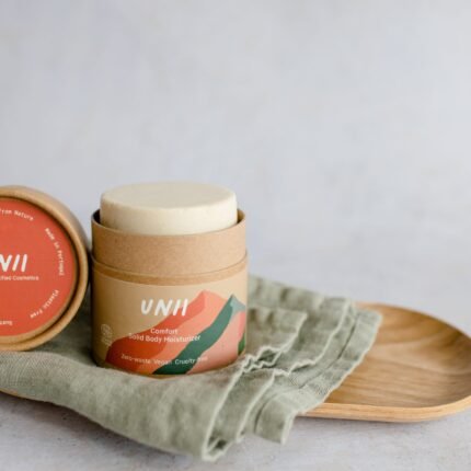 Hidratante corporal sólido Comfort da Unii colocado sobre fundo neutro, hidratante sólido biológico com extrato de bolota e manteigas nutritivas, formato sólido sustentável.